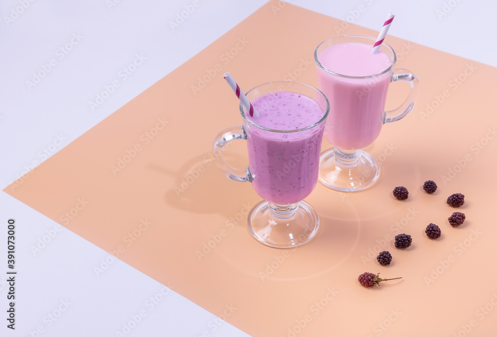 two glasses of BlackBerry and raspberry smoothies on a colored background. The concept of healthy eating two glasses of BlackBerry and raspberry smoothies on a colored background. The concept of healthy eating