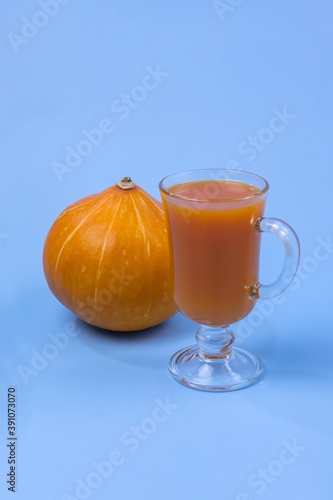 a glass of pumpkin juice and a pumpkin on a blue background