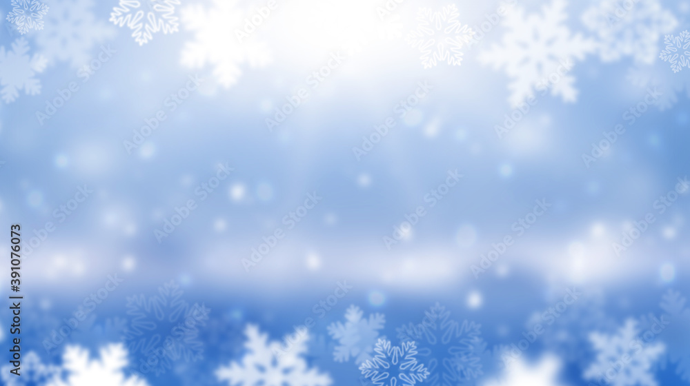 Wide blurred winter background. The sun is shining in snowflakes. Abstract blue Christmas background. Panorama.