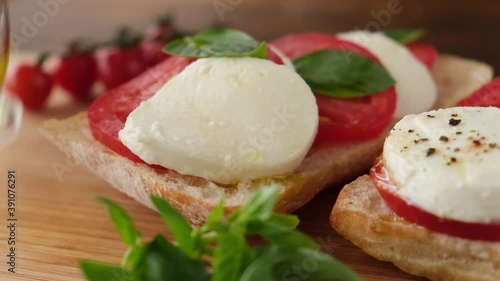 Italian panini with mozzarella cheese, tomatoes and olive oil. Closeup view. Pouring olvie oil on caprese sandwich photo