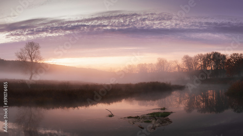Autumn landscape fog over river and sky with rising sun © SerPhoto