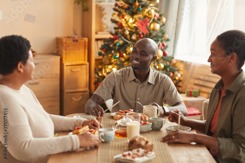 Warm toned portrait of African-American family enjoying tea and snacks while celebrating Christmas at home