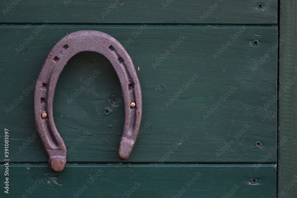Off-center old worn horseshoe nailed to a green wooden wall Off-center old worn horseshoe nailed to a green wooden wall
