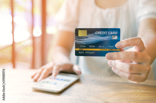 Women with credit card and using mobile phones to shop online. Close up card. Warm tones.