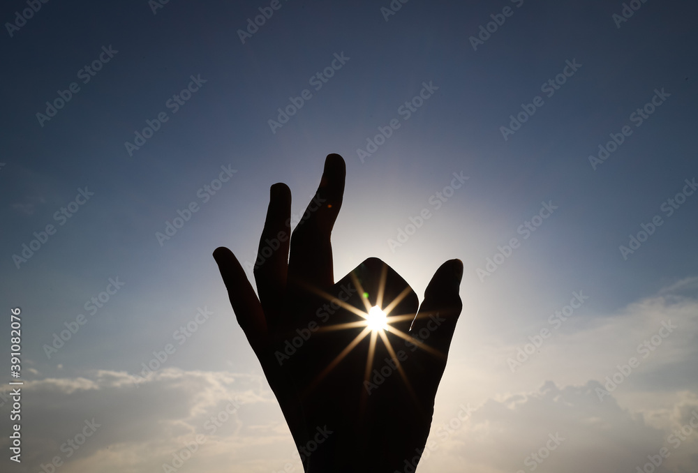 silhouette of a hand reaching for the star shaped sun