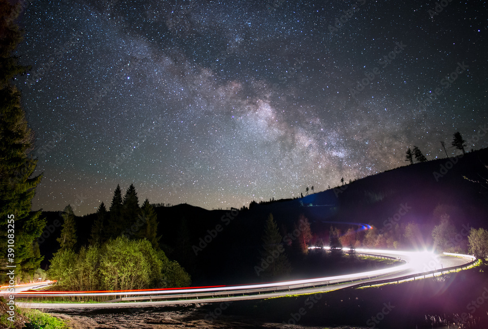 Fototapeta premium Milky way over a road light up by a car