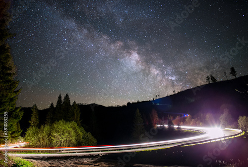 Milky way over a road light up by a car  © Mrio