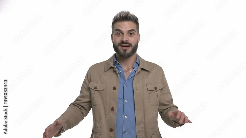 surprised young guy wearing beige jacket shockingly opening mouth, holding fists in the air and celebrating, screaming and laughing isolated on white background in studio surprised young guy wearing beige jacket shockingly opening mouth, holding fists in the air and celebrating, screaming and laughing isolated on white background in studio