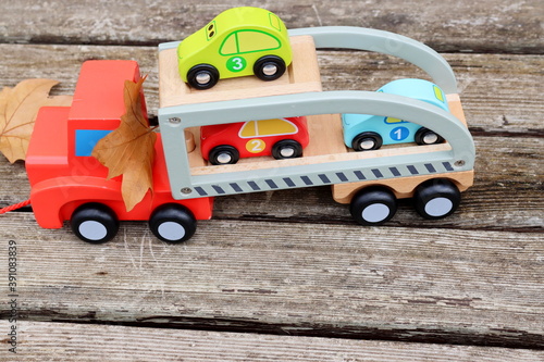 Big and small Wooden toy cars and autumn leaves on a wooden table.