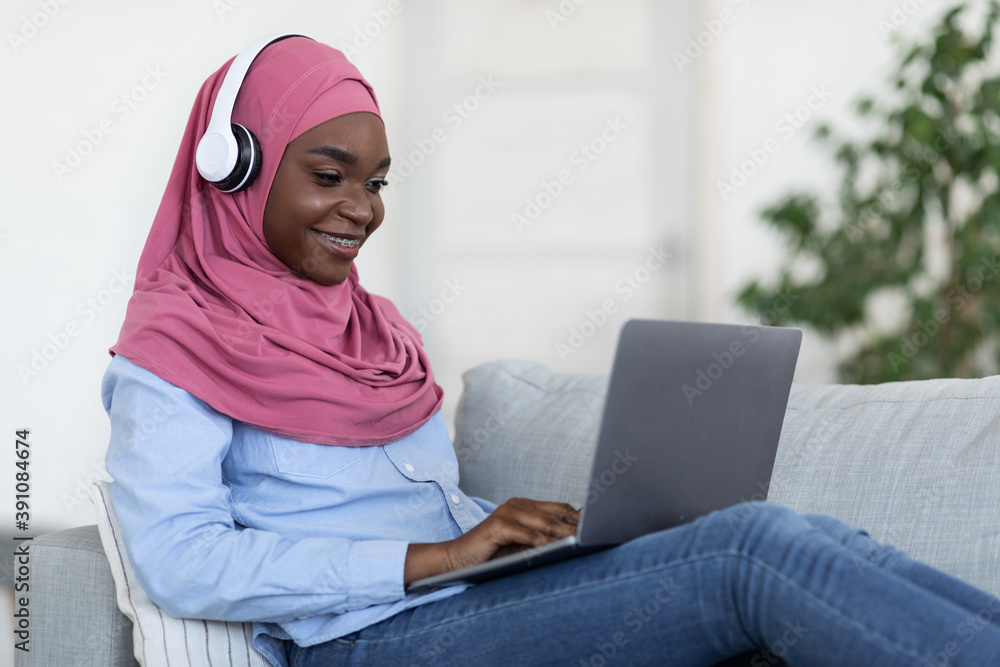 Black Muslim Woman In Hijab Studying With Laptop And Headphones At Home Black Muslim Woman In Hijab Studying With Laptop And Headphones At Home