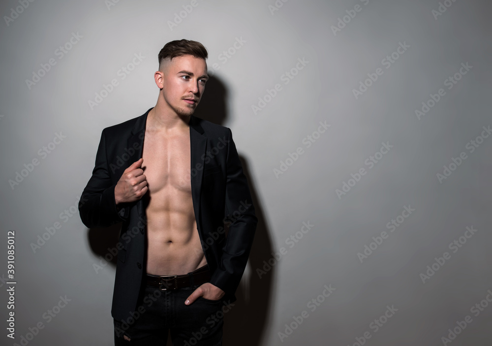Handsome young bodybuilder with fit and athletic build wearing blazer on grey background Handsome young bodybuilder with fit and athletic build wearing blazer on grey background