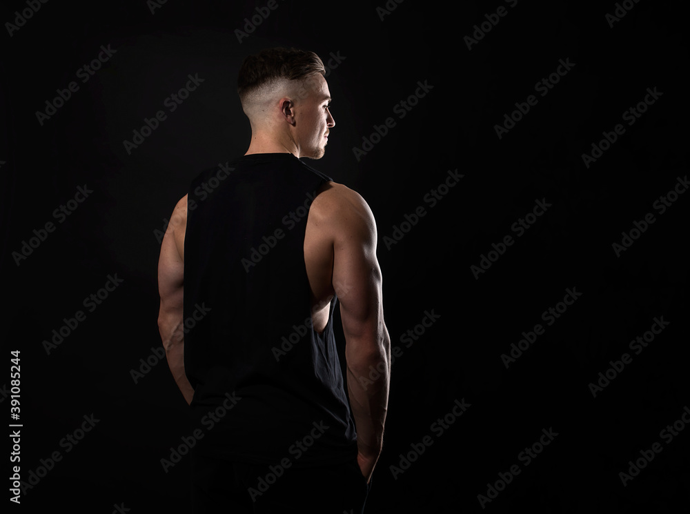 Handsome and fit bodybuilder posing on black background in workout gear Handsome and fit bodybuilder posing on black background in workout gear