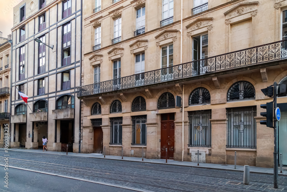 Bordeaux, France. Street in the downtown, tram line and historical house with typical french windows and long balcony.