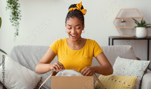 Happy black woman unpacking box after online shopping photo