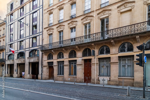 Bordeaux, France. Street in the downtown, tram line and historical house with typical french windows and long balcony.