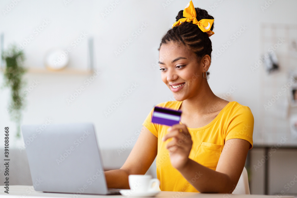 Black woman using laptop and credit card at home Black woman using laptop and credit card at home