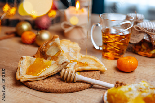 christmas table setting. homemade christmas russian pancakes withhoney dripping from a spoon.  photo