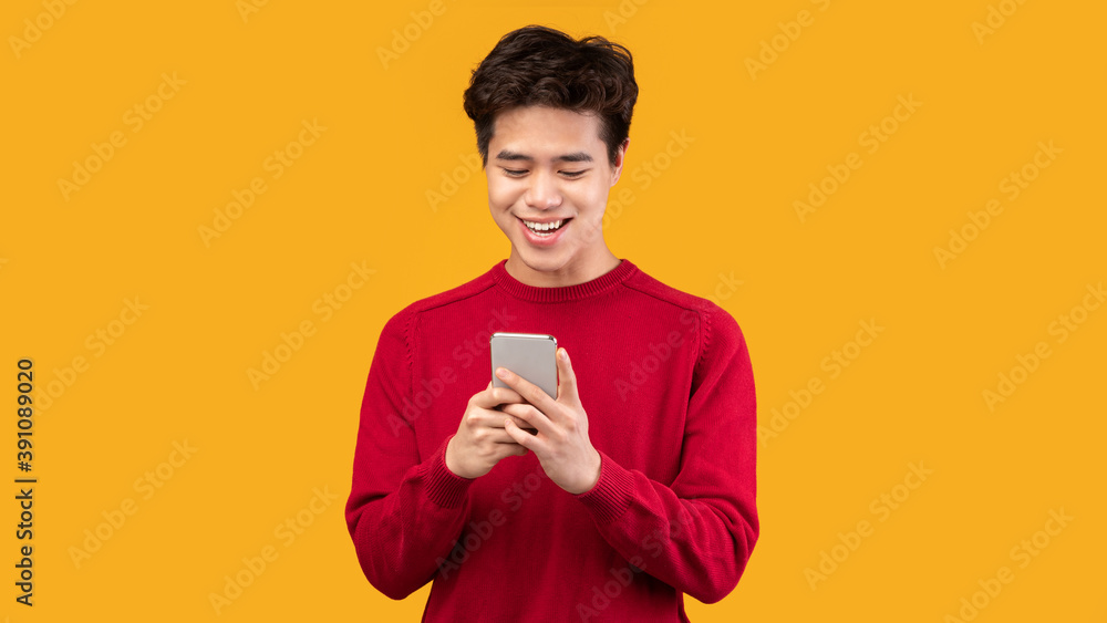 Happy asian guy using his mobile phone at studio Happy asian guy using his mobile phone at studio