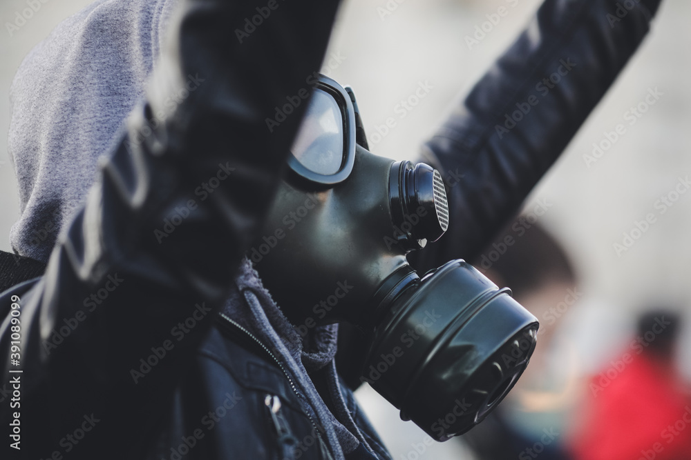 Shallow depth of field (selective focus) image with a protestor wearing a hoodie and a military gas mask. Shallow depth of field (selective focus) image with a protestor wearing a hoodie and a military gas mask.