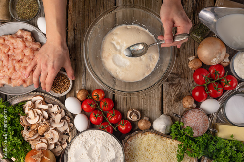 Chef hands makes dough for pie on wooden rustic table with variety of ingredients background. Concept of cooking process. Backstage of preparing tasty meal. View from above. Flat lay.