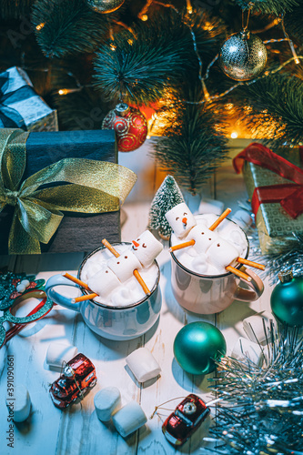 a mug with hot chocolate on a wooden table with a marshmallow man who is resting in a mug photo