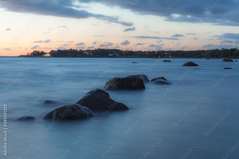 Sunset over the sea. Stones on the foreground. Long exposure