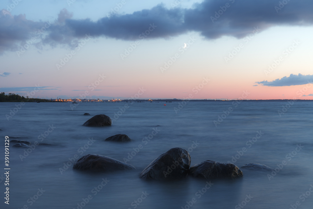 Sunset over the sea. Stones on the foreground. Long exposure