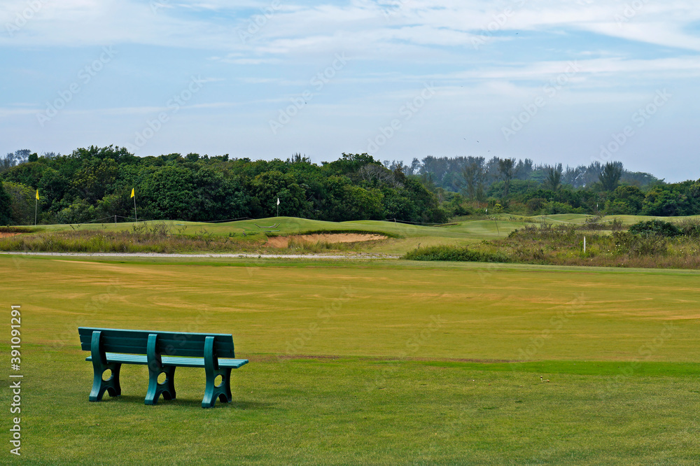 Green bench in front of golf course