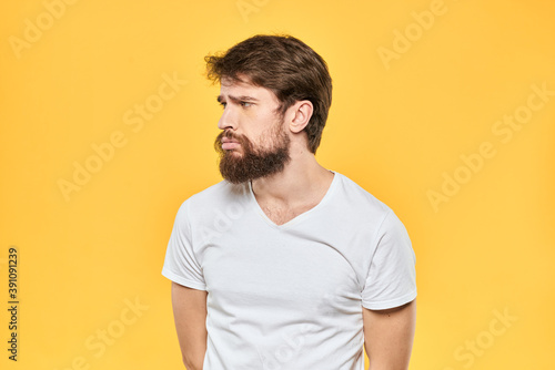 Bearded man emotions gestures with hands facial expression white t-shirt yellow background
