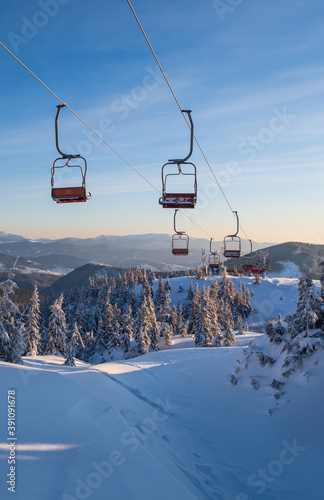 Alpine resortr ski lift with seats going over the sunrise mountain skiing freeride slopes and fir tree groves
