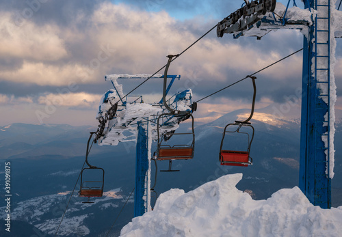 Alpine resortr ski lift with seats going over the sunset mountain skiing  slopes in extremally windy weather photo