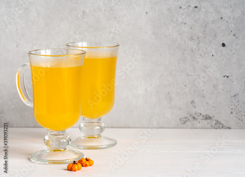 A beautiful healthy drink from sea buckthorn in two glasses on a light background.