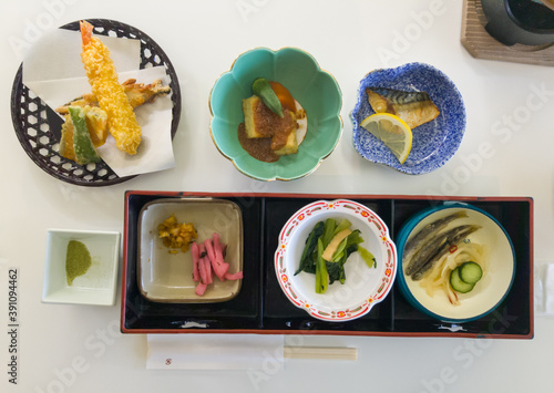 A japanese lunch set meal with fried shrimp, tofu, ginger, spinach and fish in top view