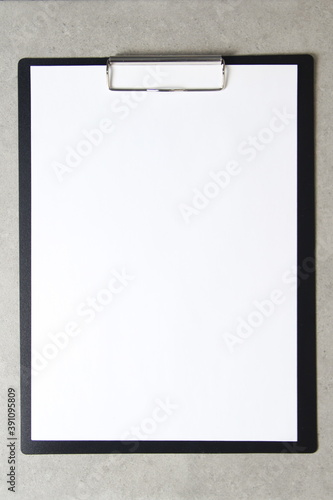 Template of white paper on light grey concrete background in a black tablet with a clip. Concept of new idea, business plan and strategy, empty space for text