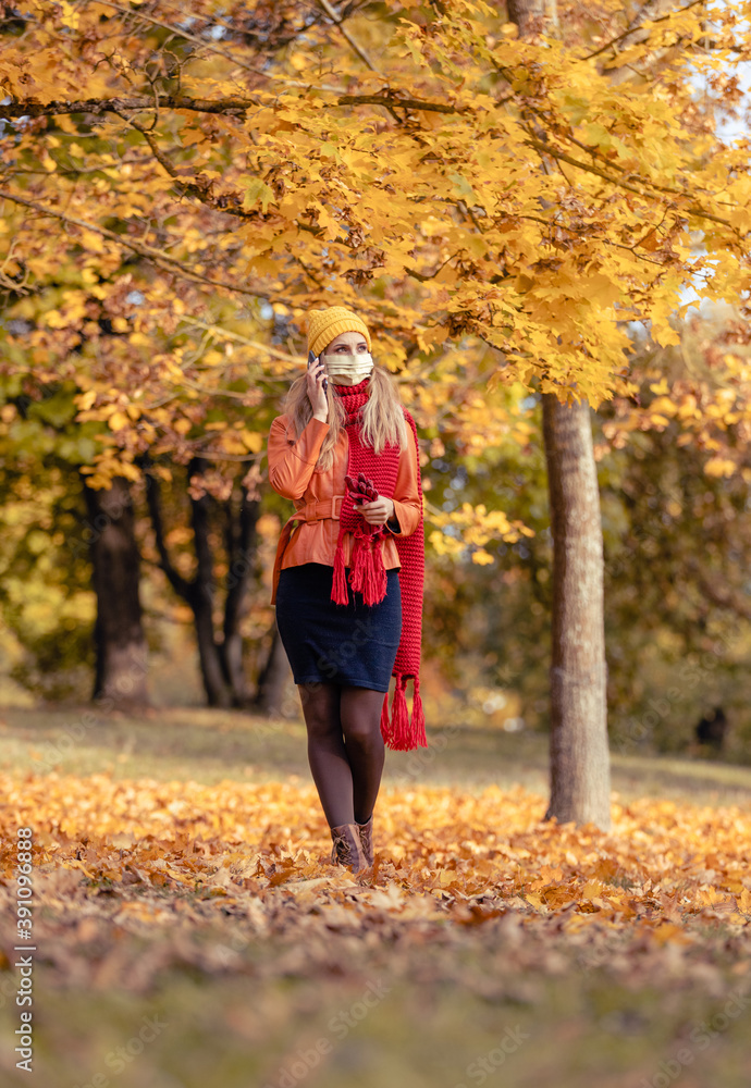 Woman using her phone having walk in fall park during coronavirus crisis Woman using her phone having walk in fall park during coronavirus crisis