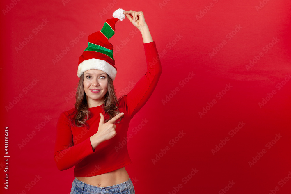 a young woman in a red and green dwarf cap points her fingers at the text space. a young woman in a red and green dwarf cap points her fingers at the text space.