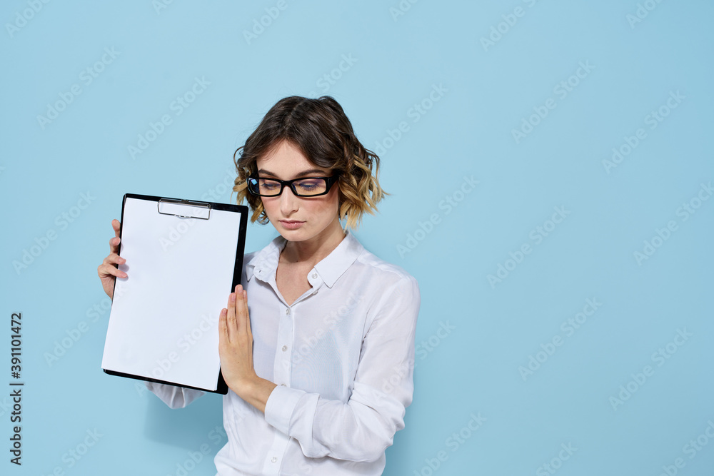Business woman with documents in a folder on a blue background and in a light shirt glasses on her face Business woman with documents in a folder on a blue background and in a light shirt glasses on her face