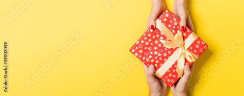 Top view of a man and a woman giving and receiving gift for a holiday on colorful background. Love and relationship concept with copy space
