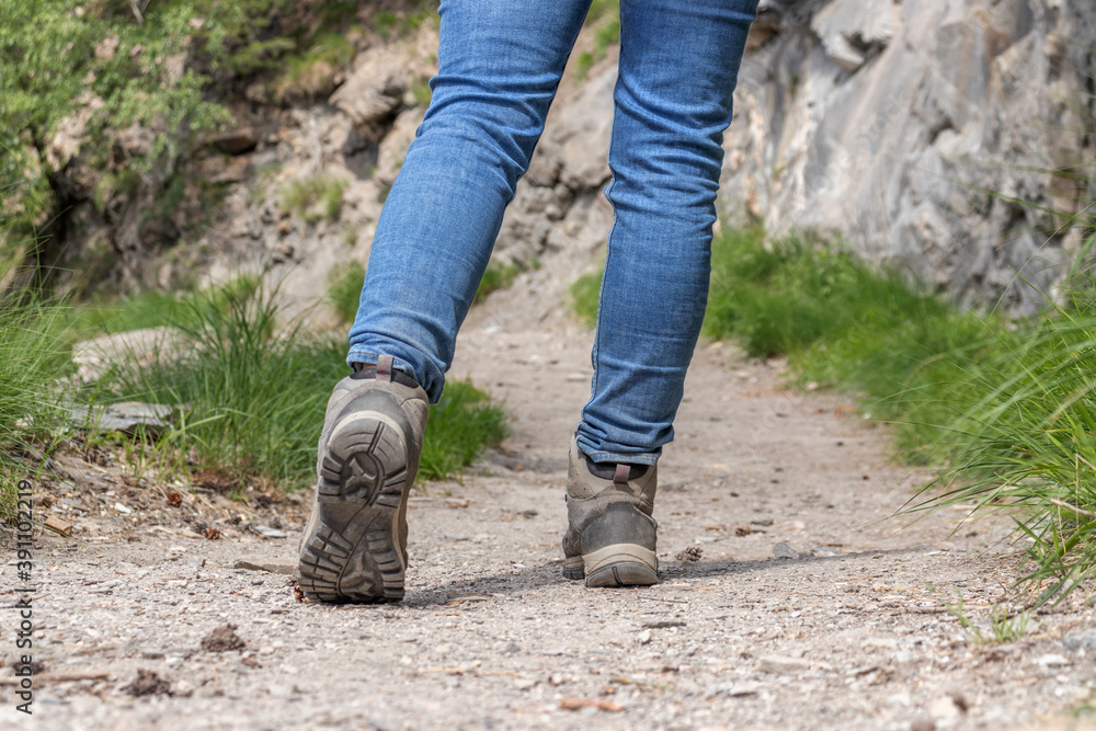 hiking shoes in action on a mountain gravel path surrounded by grass. Close-up of female hikers shoes. hiking shoes in action on a mountain gravel path surrounded by grass. Close-up of female hikers shoes.