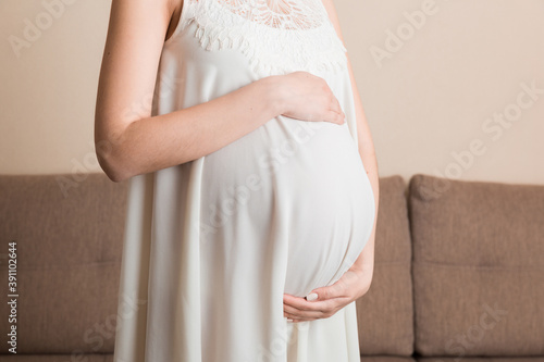 Pregnancy woman in beautiful dress standing on the home