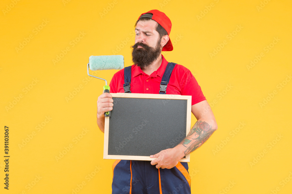 Welcome to my world. repair and building. craftsman on construction. reconstruction advertising. bearded man with paint roller and board. painter at painting works. hipster with copy space on board Welcome to my world. repair and building. craftsman on construction. reconstruction advertising. bearded man with paint roller and board. painter at painting works. hipster with copy space on board