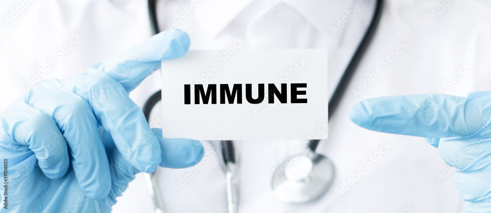 in the hands of a doctor a card with the text IMMUNE, close-up. Medical concept. in the hands of a doctor a card with the text IMMUNE, close-up. Medical concept.