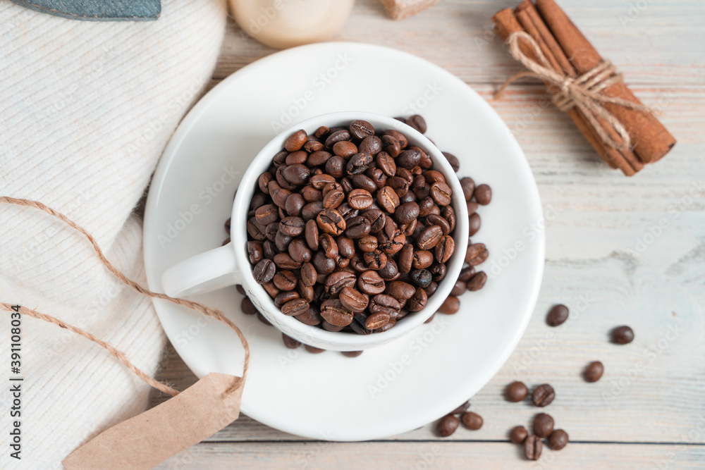 Fototapeta premium Coffee bean Cup, sweater and cinnamon on a white wooden background. The view from the top. Concept of coffee backgrounds.