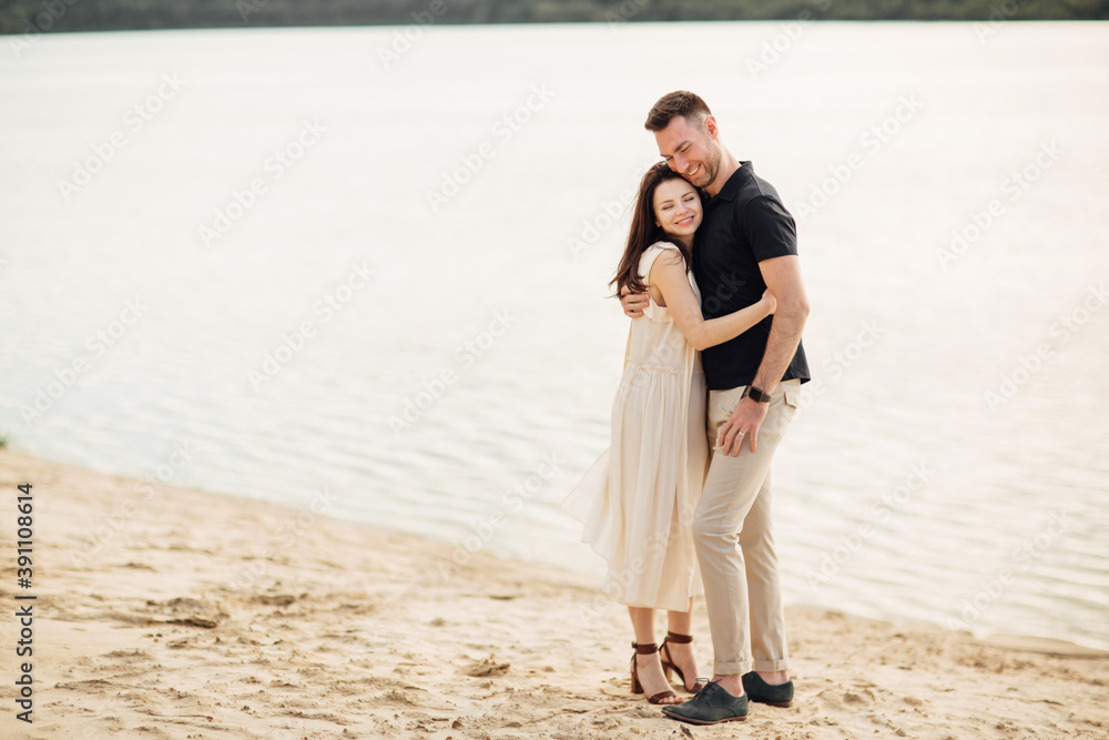Romantic couple is hugging outdoors. elegant and stylish woman and man in love are walking along the lake. Happy moments together. love story Romantic couple is hugging outdoors. elegant and stylish woman and man in love are walking along the lake. Happy moments together. love story