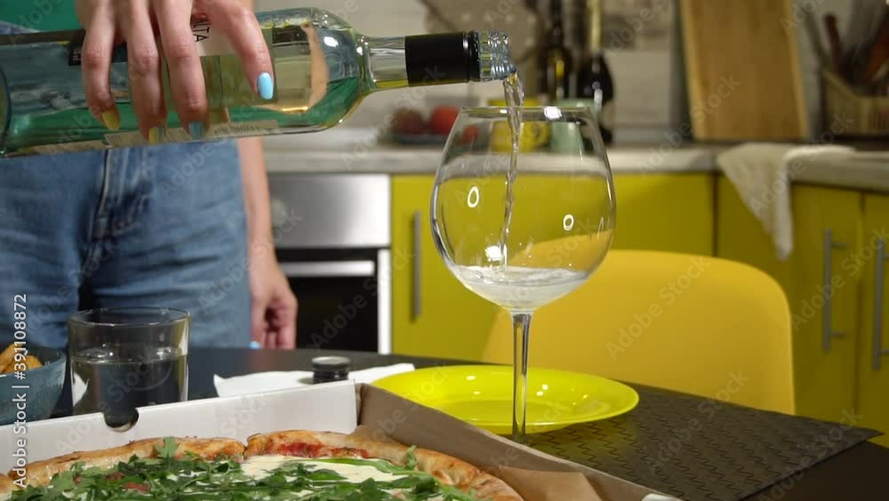 Close-up of hand woman filling wine glass with white wine in slow motion at home dinner Close-up of hand woman filling wine glass with white wine in slow motion at home dinner