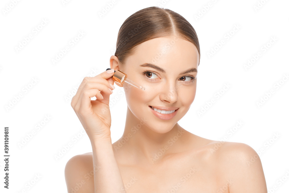 Young woman applying serum to face, looking away, isolated on white background. Beautiful model with perfect clean skin. Cosmetic ads concept Young woman applying serum to face, looking away, isolated on white background. Beautiful model with perfect clean skin. Cosmetic ads concept