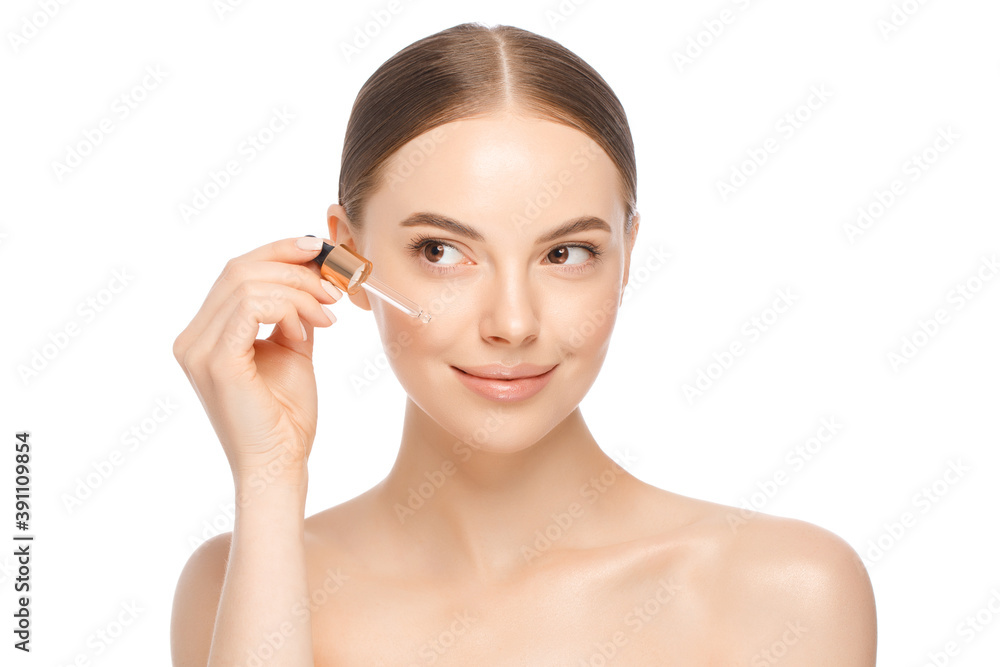 Close-up portrait of young beautiful female holding pipette with cosmetic serum or natural oil near face, isolated on white background