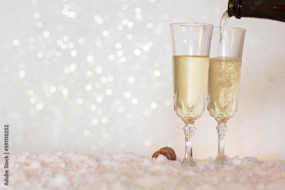 Pouring champagne from bottle into glass on snow with bokeh background with copy space Pouring champagne from bottle into glass on snow with bokeh background with copy space