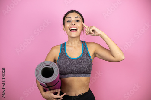 Young beautiful woman wearing sportswear over isolated pink background holding a splinter in her hand smiling and thinking with her fingers on her head that she has an idea.