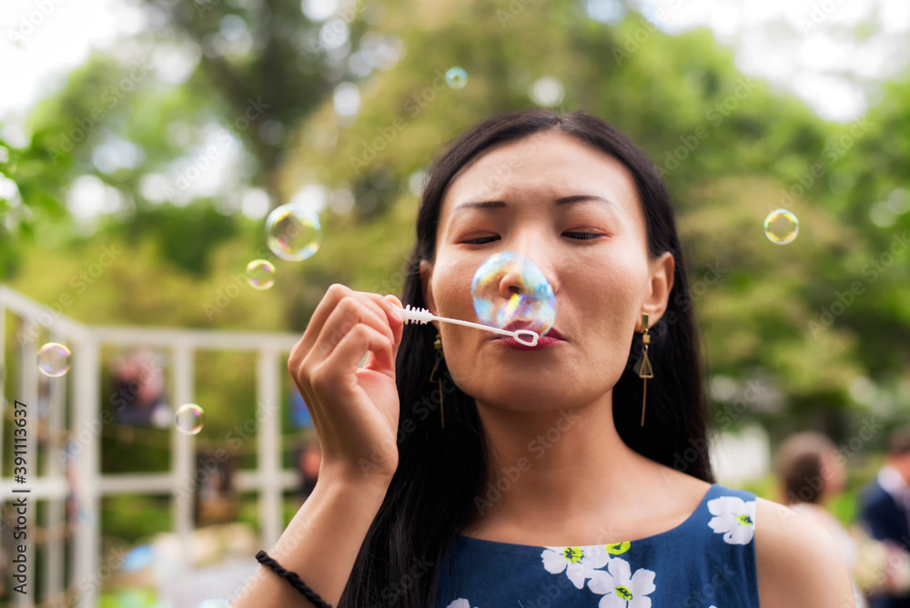 Chinese woman blowing bubbles outside on a summer day Chinese woman blowing bubbles outside on a summer day